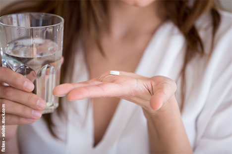 Frau mit Tablette in der Hand profitiert von den Vorteilen der Kupferkette ohne Hormone