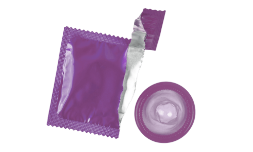 Lila Kondomverpackung mit geöffnetem Rand und daneben ein entfaltetes Kondom – Symbolbild für gerissenes Kondom, Verhütungspanne und Notfallverhütung.